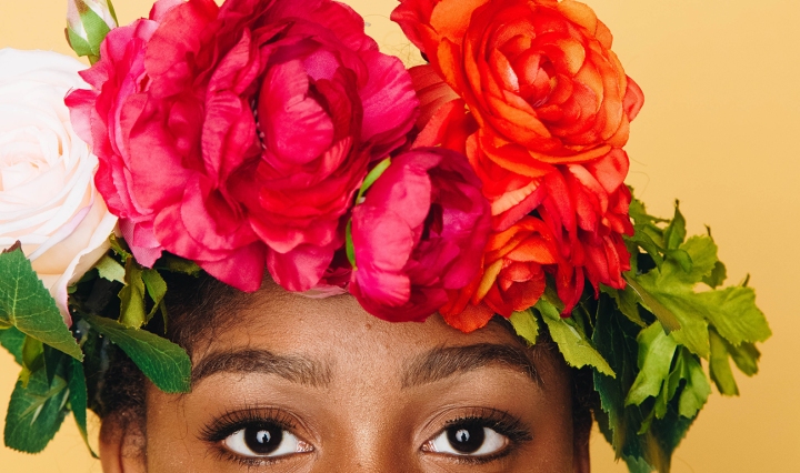The top of a Black woman's face. She wears a crown of bright flowers