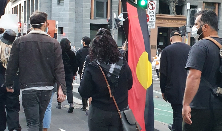 Protesters at the Stop Black Deaths in Custody march in Sydney. One man carries the Aboriginal flag