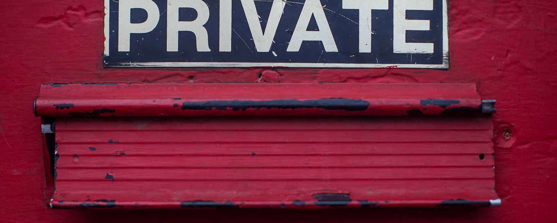 A red door with letterbox, Sign above says "Private"